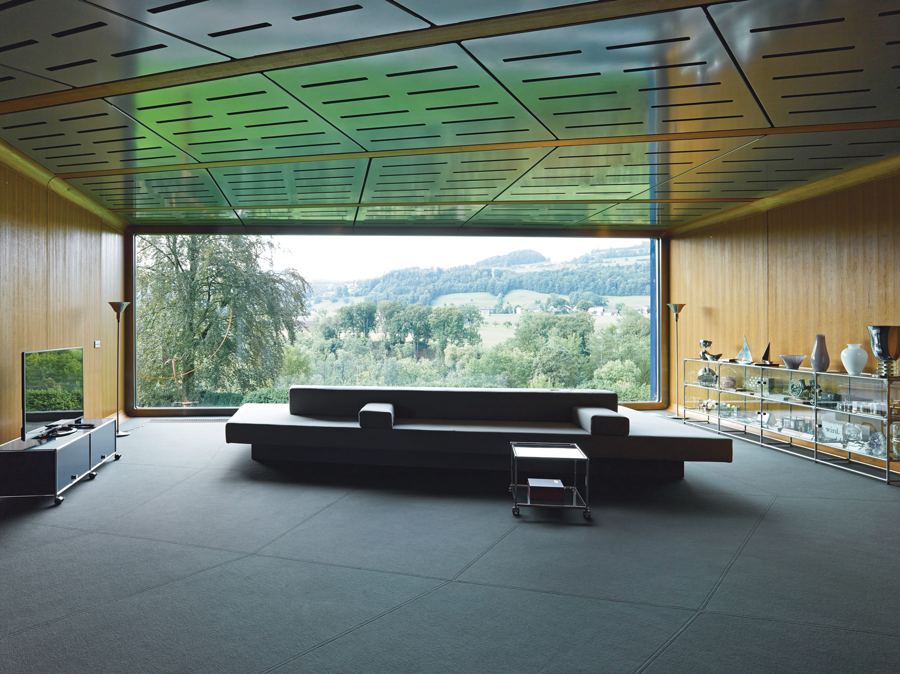 A sofa designed by architect Ali Tayar dominates a carbon fiber-framed living room in Bern, Switzerland. One side of the sofa is meant for reclining; the other for sitting. the rest of the furniture is from USM Haller Systems. (Courtesy Simon B. Opladen)