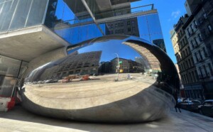 mirrored sculpture between building and sidewalk