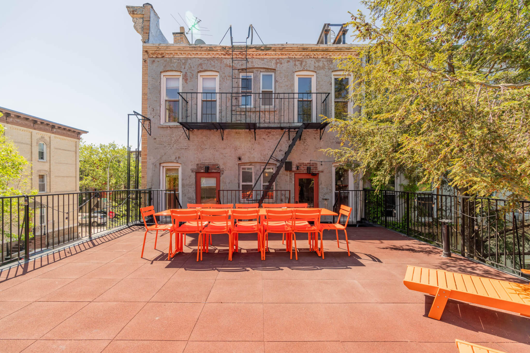 Urban rooftop terrace with bright orange furniture.