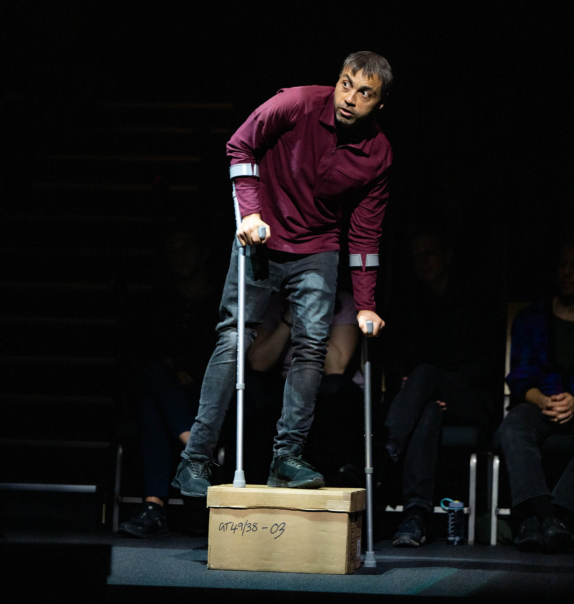 a man walks across stage using crutches