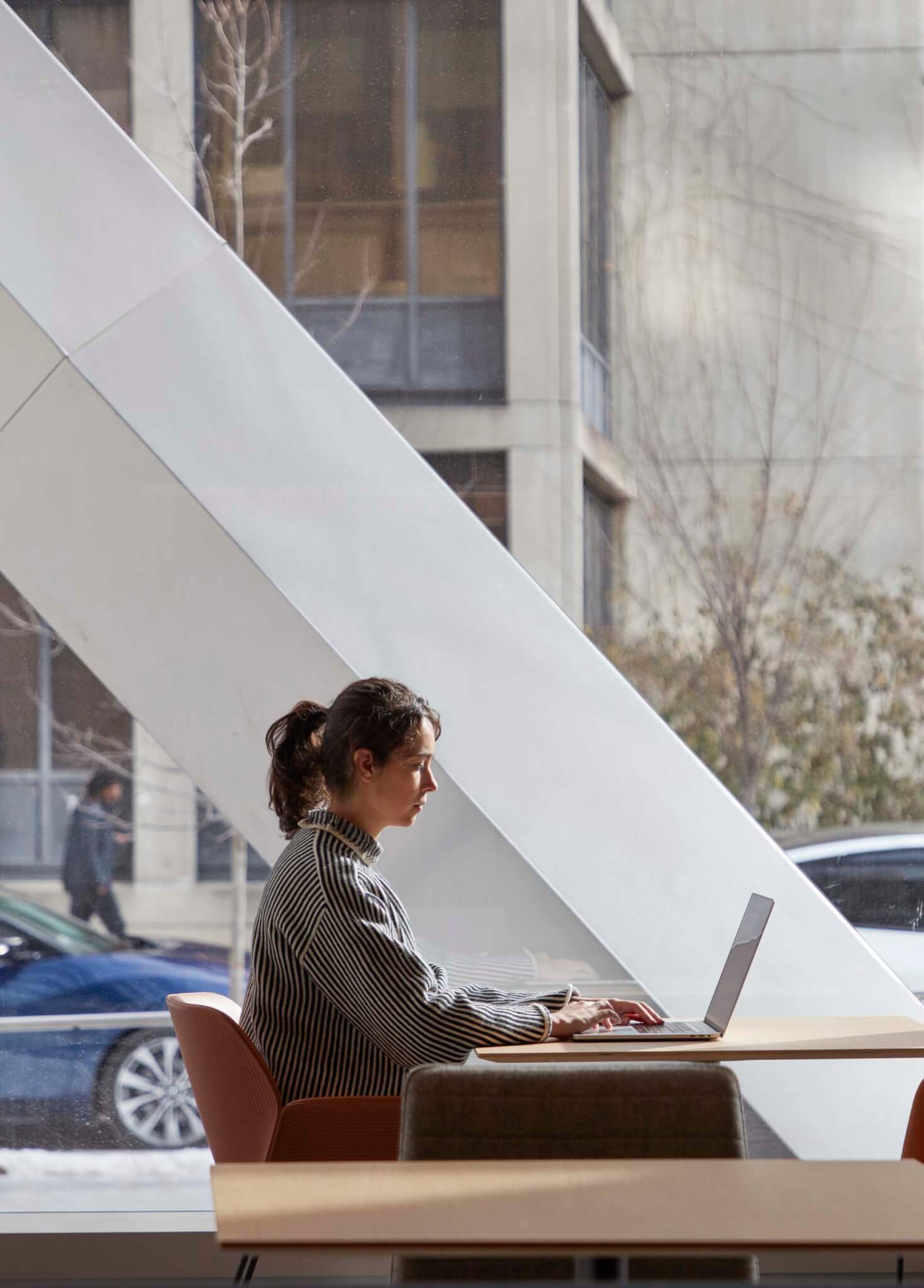 person working on laptop with glass behind them