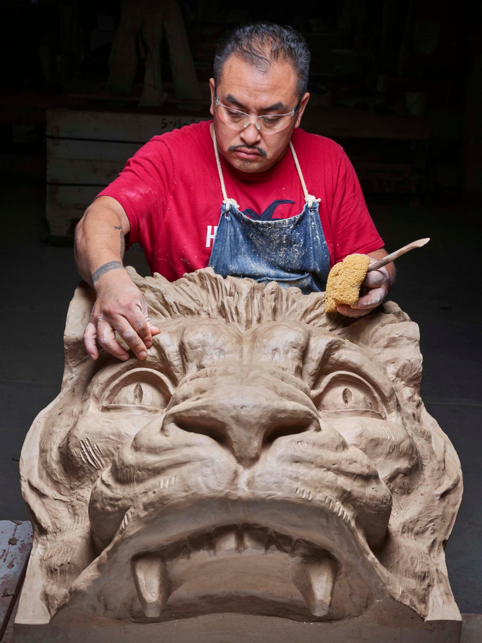 man restoring large lion head