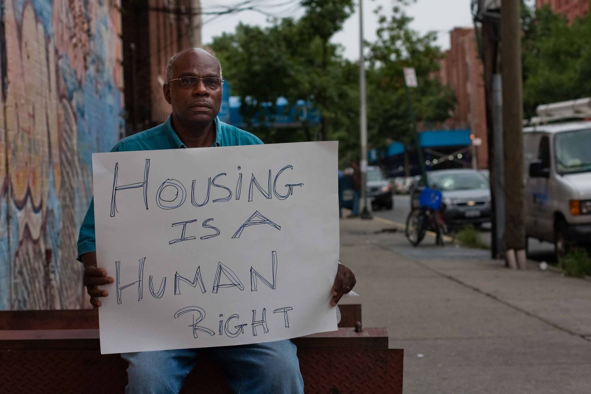 man holding sign that reads housing is a human right