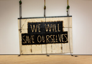 Large art piece by Theaster Gates that reads We Will Save Ourselves