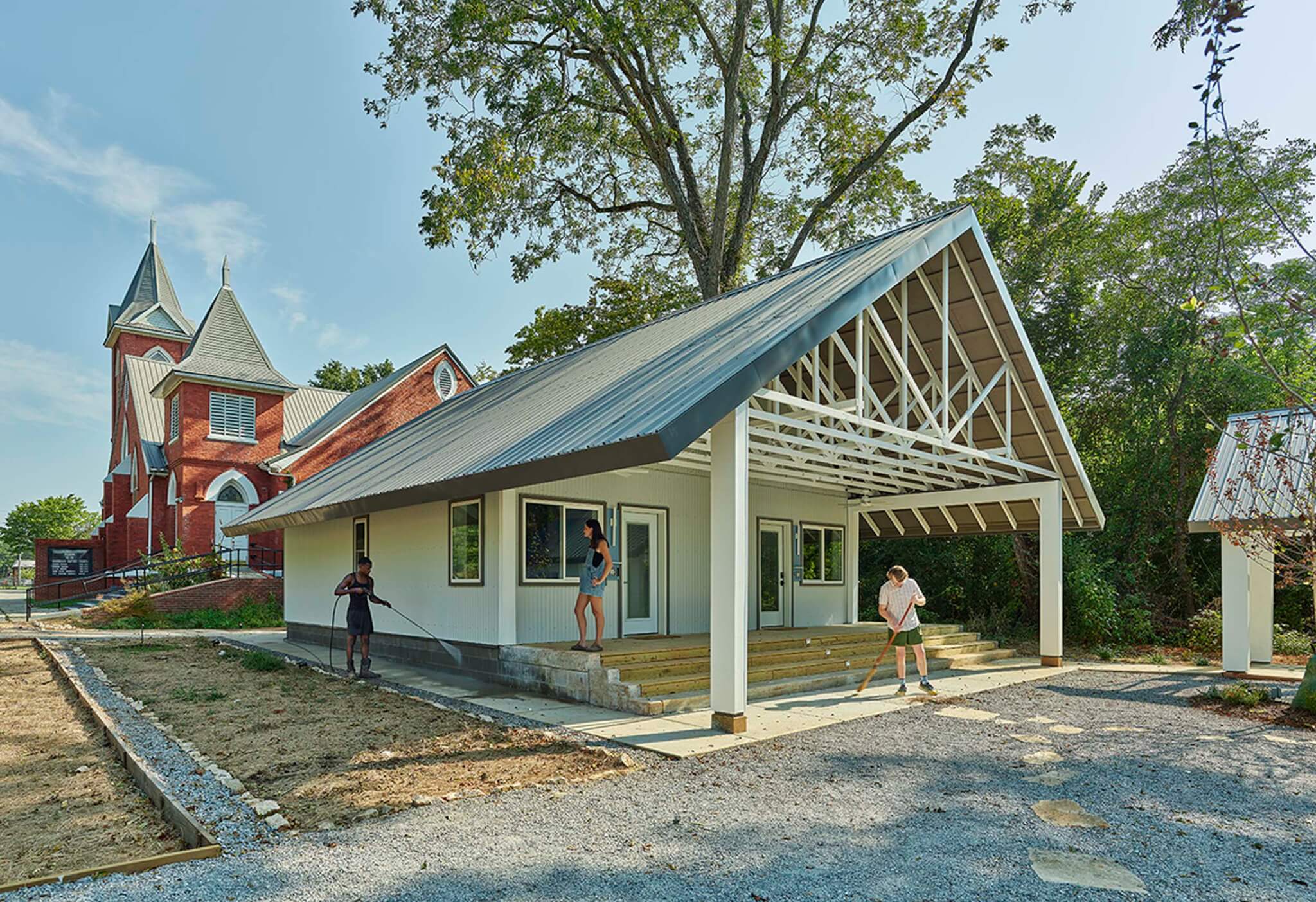 house by Rural Studio with historic building behind it