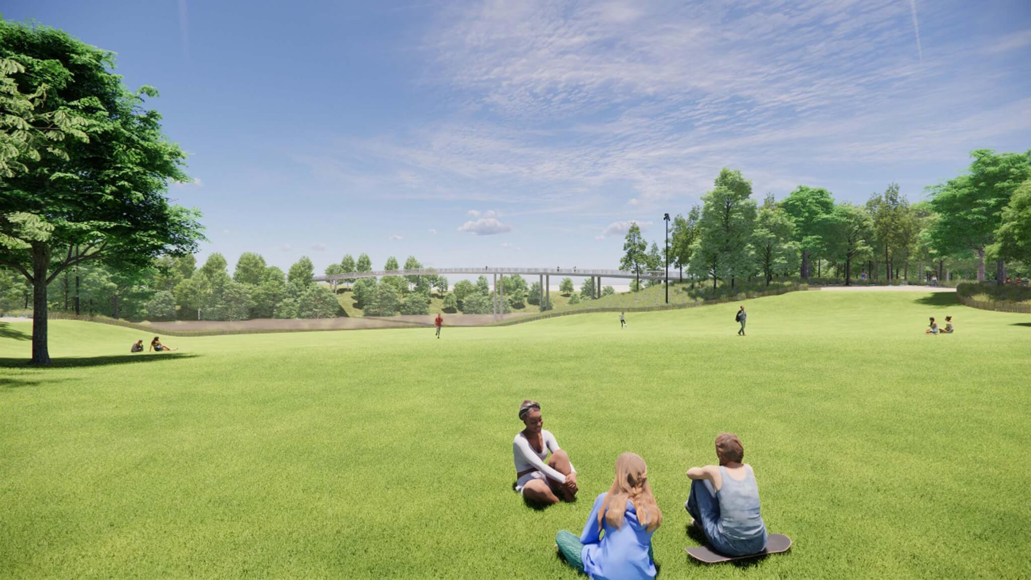 people sitting on a grassy lawn with a pedestrian bridge in the distance