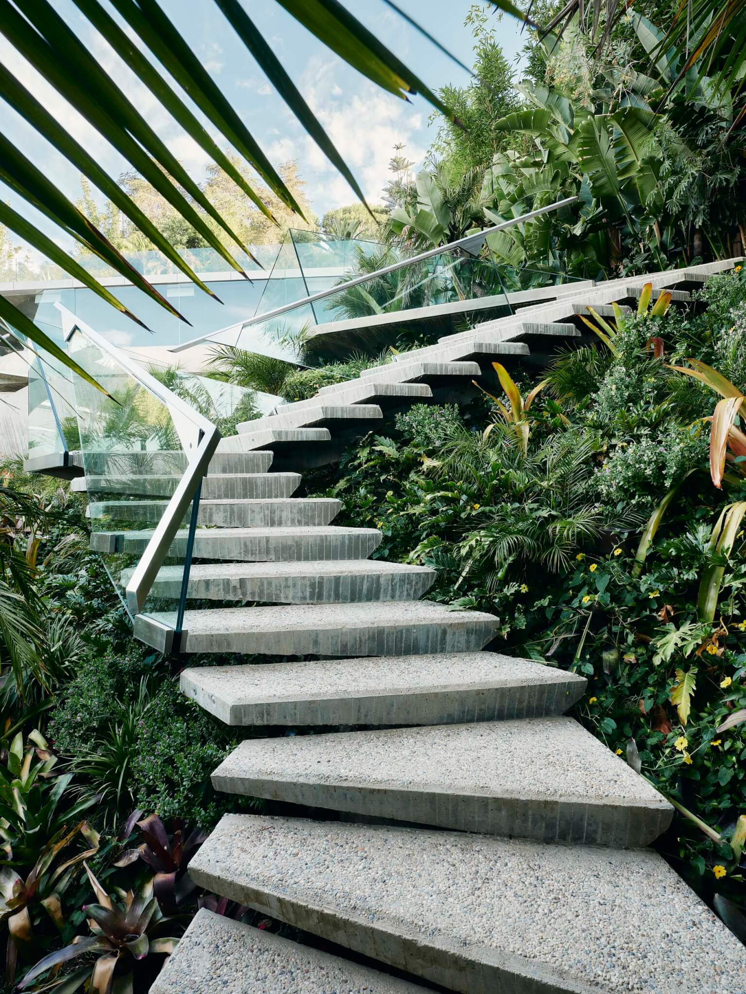 Stairs made of board formed concrete and framed by clear glass railings