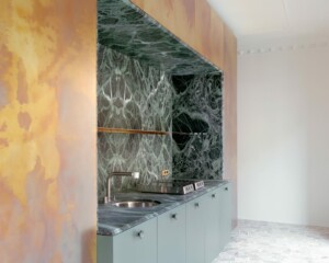 A kitchen is clad in a brass box with green marble