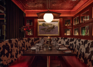 A red bar banquette with cow-print seating was designed by North 45 Projects for Auric Room