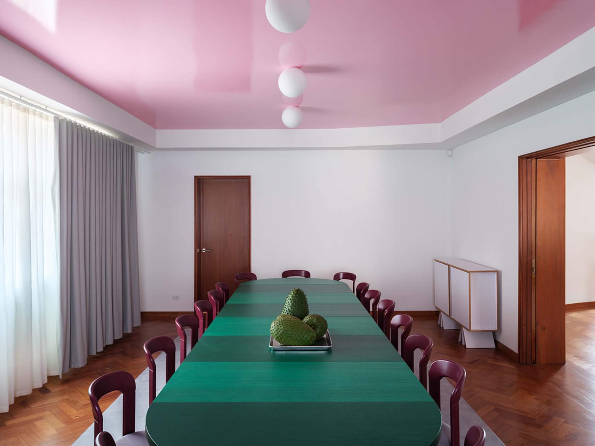 A colorful dining-style room with a green table and pink ceiling at the Swiss embassy