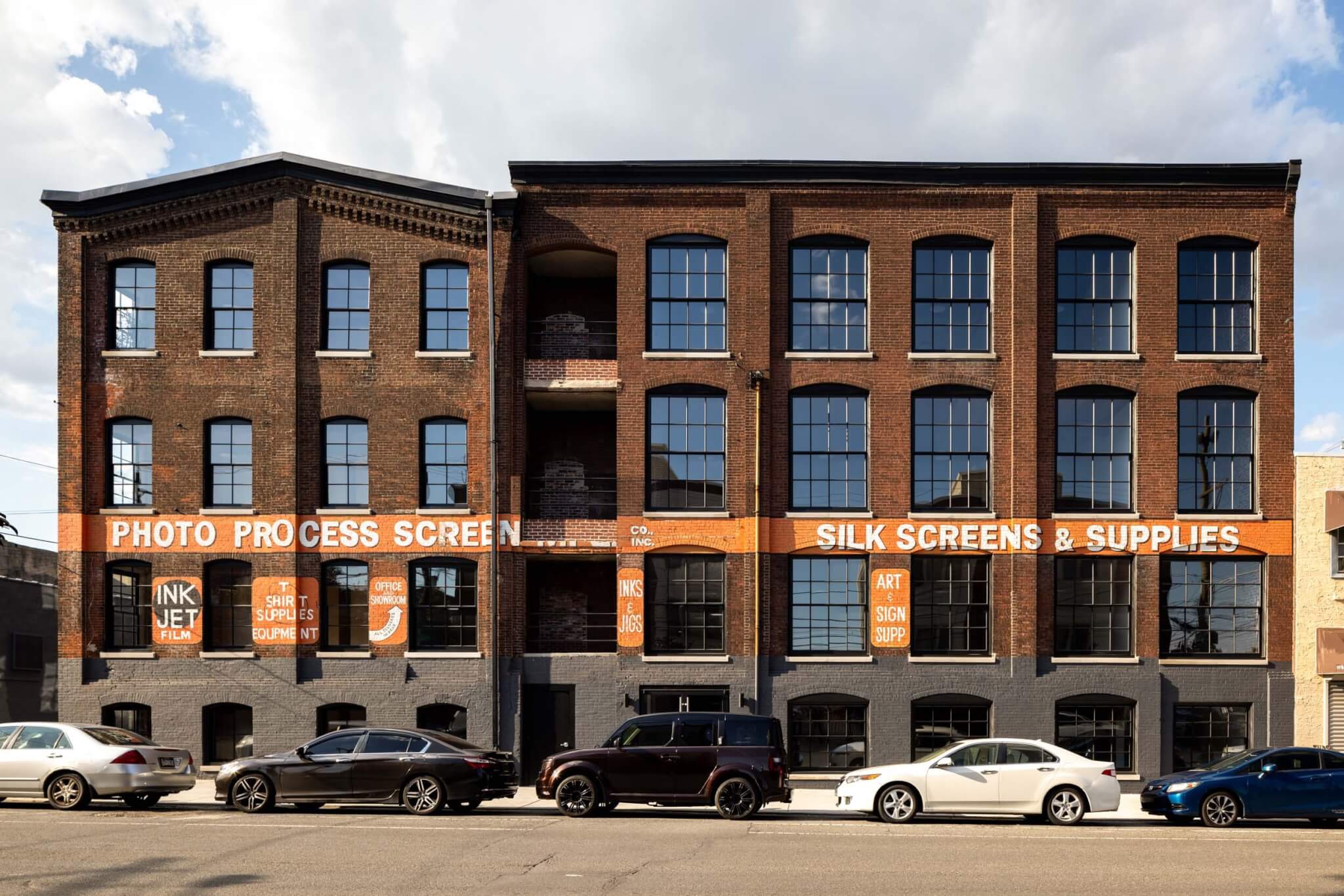 A 4-story warehouse wioth organge signage painted across its exterior was redesigned by Kaminski+Pew