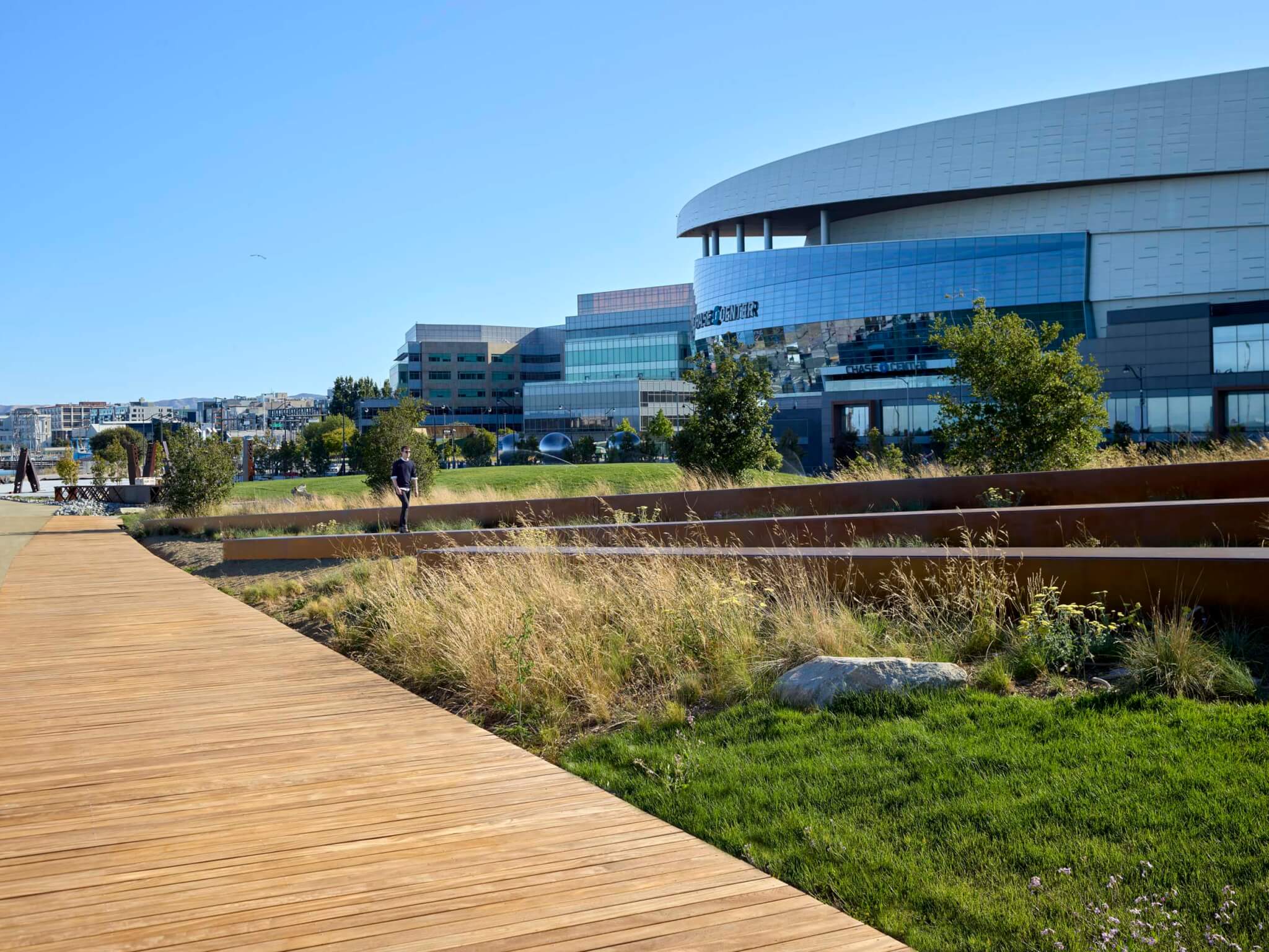 grass and lawn with building in background and wood boardwalk in front