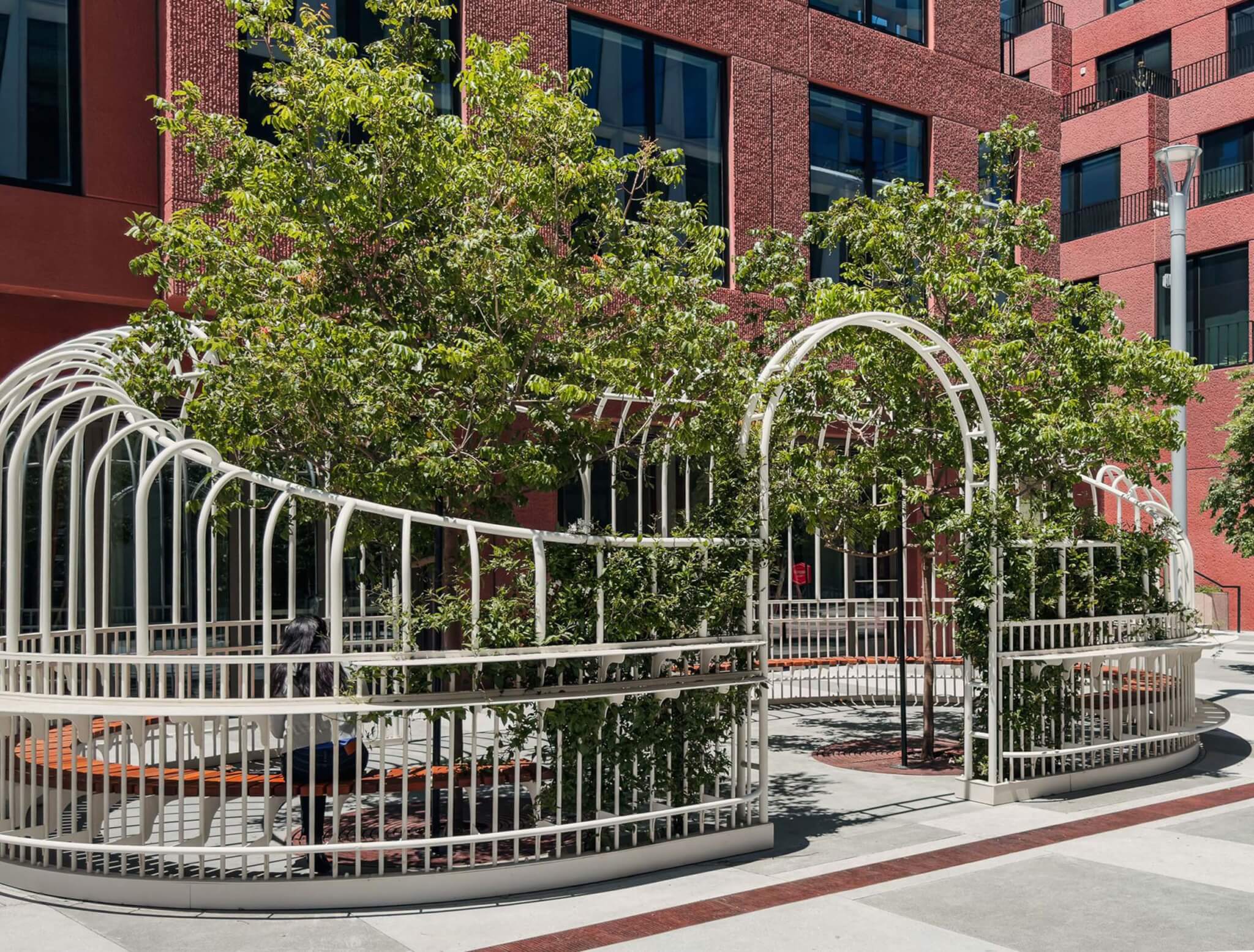 white gate surrounding trees in a public plaza outside a building