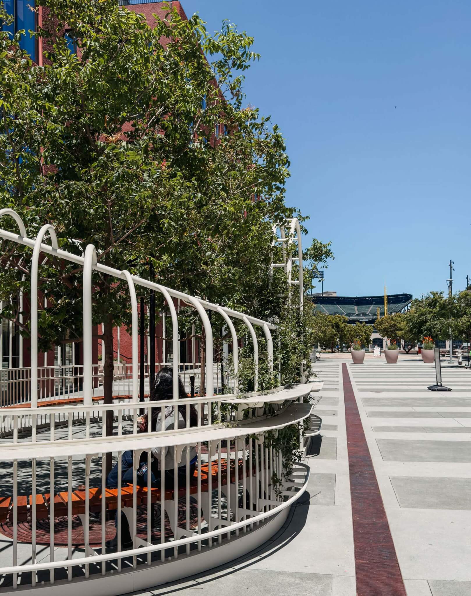 close-up of white gate surrounding trees in a park designed by Min Design in a public plaza outside a building