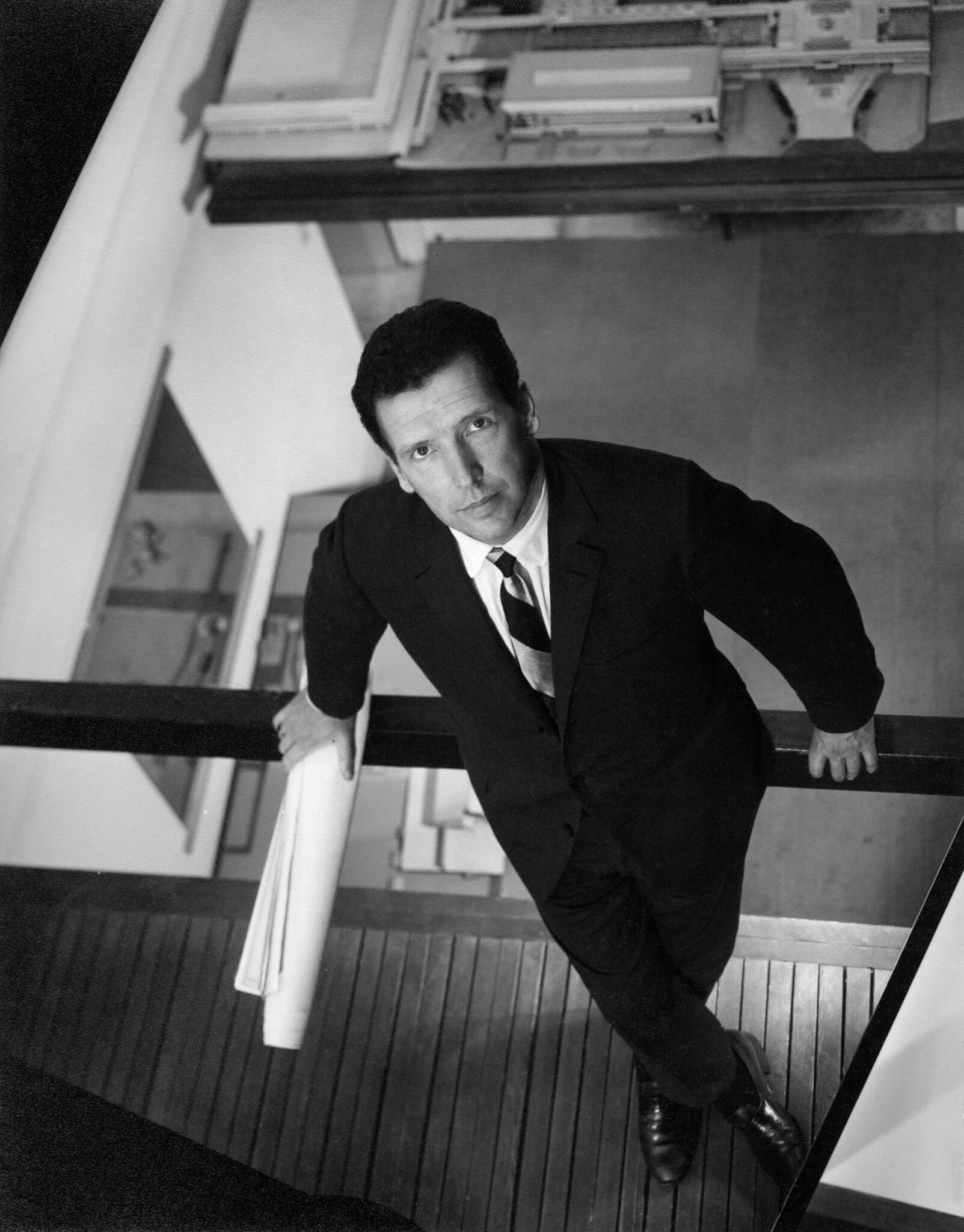 a black and white image of Arthur Erickson leaning against a railing