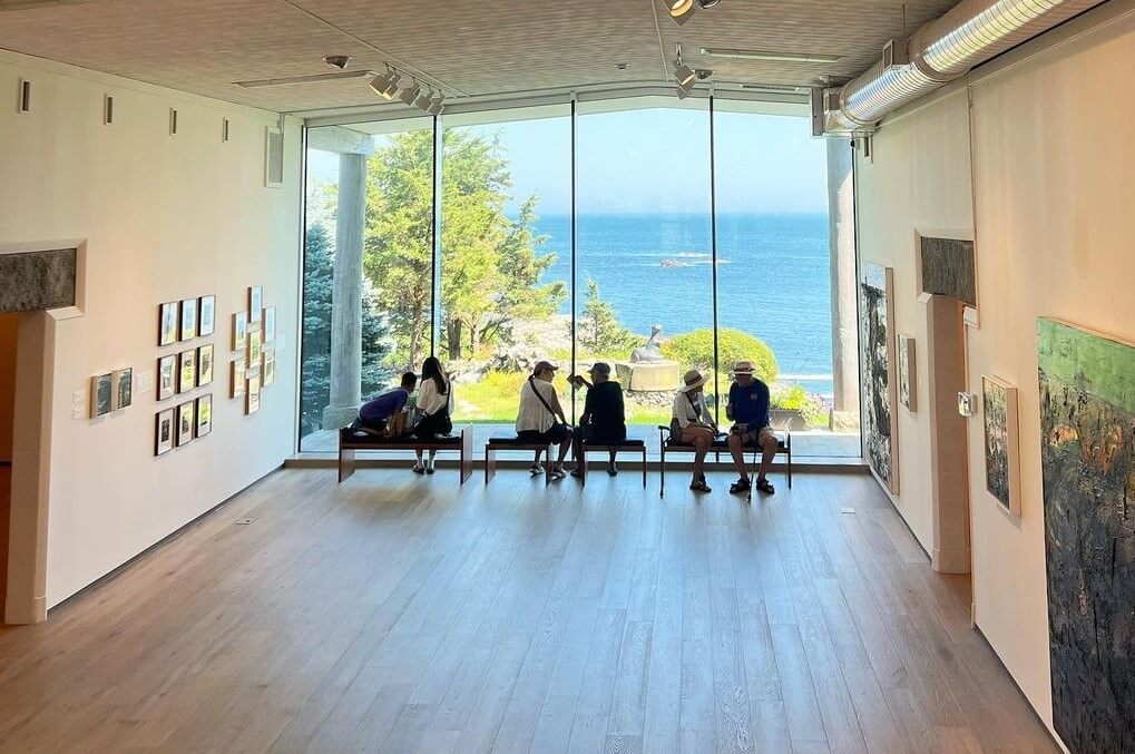 large windows looking at ocean with people on benches