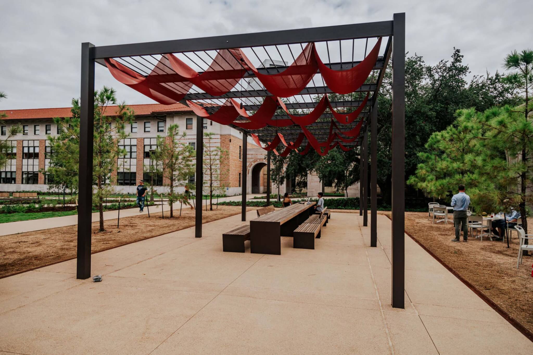 a shade pavilion with a bench and table underneath it